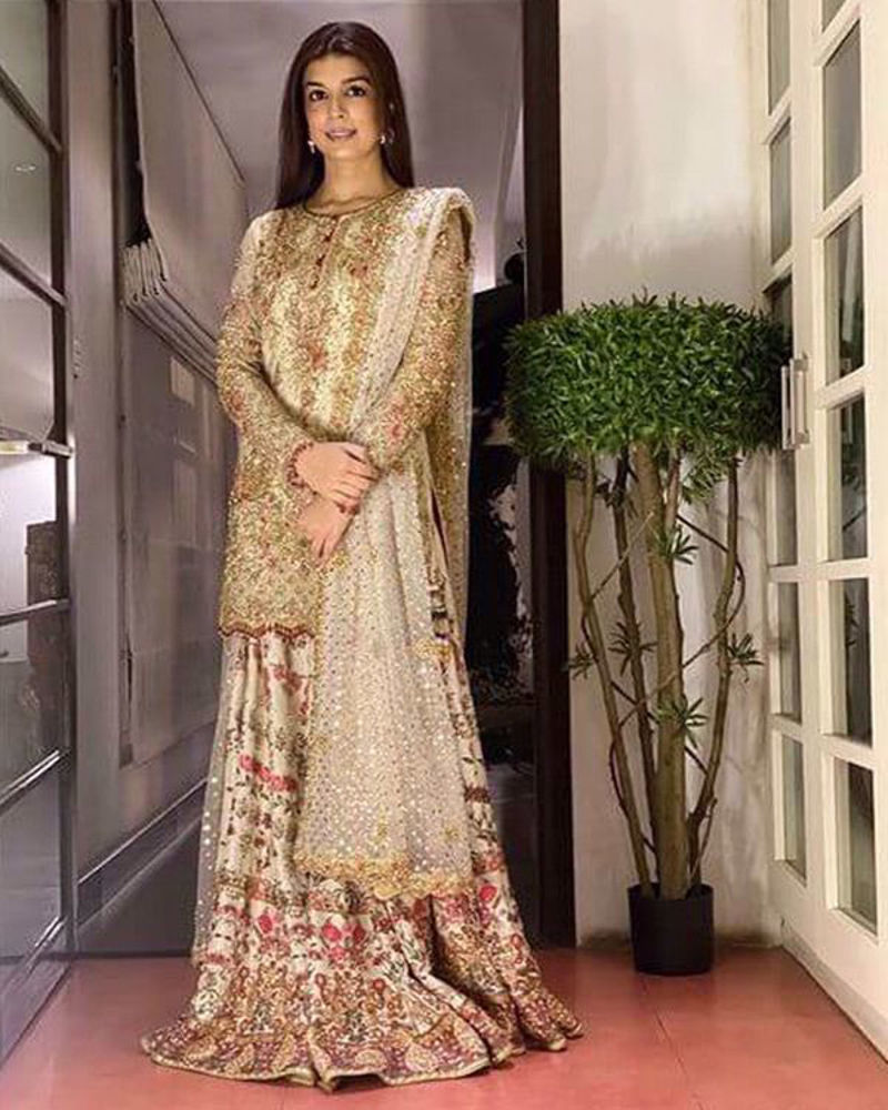 Picture of Zainab Cheema wears a dhakka pyjama and shirt in ivory and gold with kundun details, and a touch of reds and pinks.