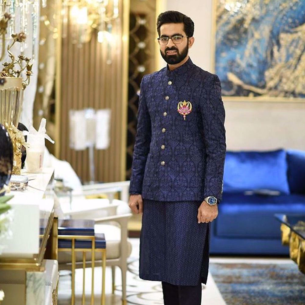 Picture of Ahsan Rafiq in a tailored midnight blue embroidered prince coat with a midnight kurta and straight pants at his pre wedding dinner.