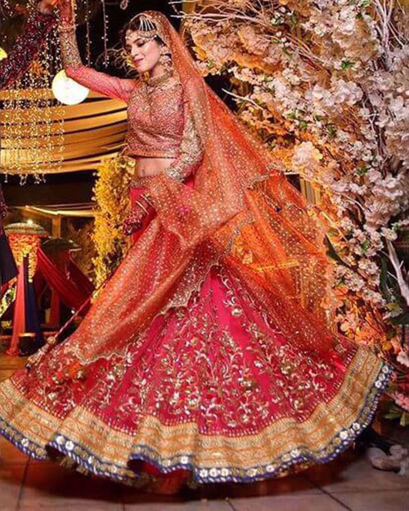 Picture of Manal wears our customized mehndi bridal in bright pink with intricate gold embellishments and a peach net dupatta