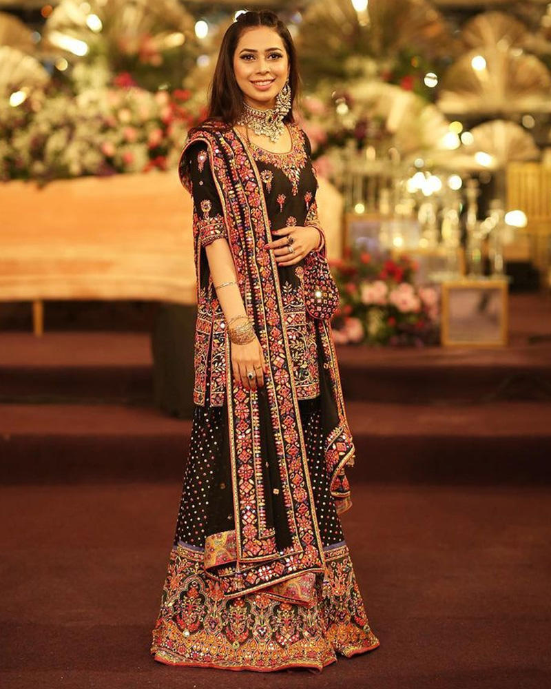 Picture of Neha in a truck art inspired combination, setting light to a black base with coloured mirrorwork and a bordered dupatta.